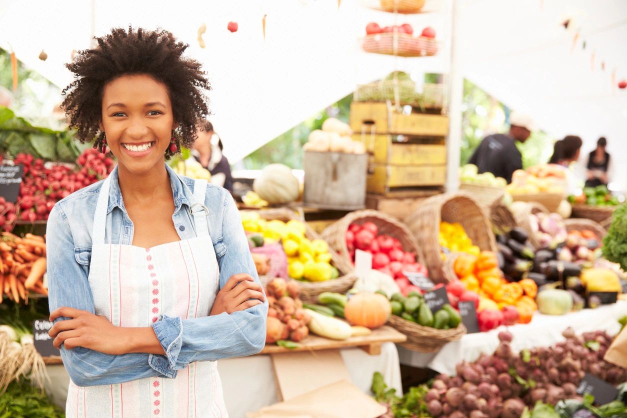 A woman standing in front of a table full of fruits.